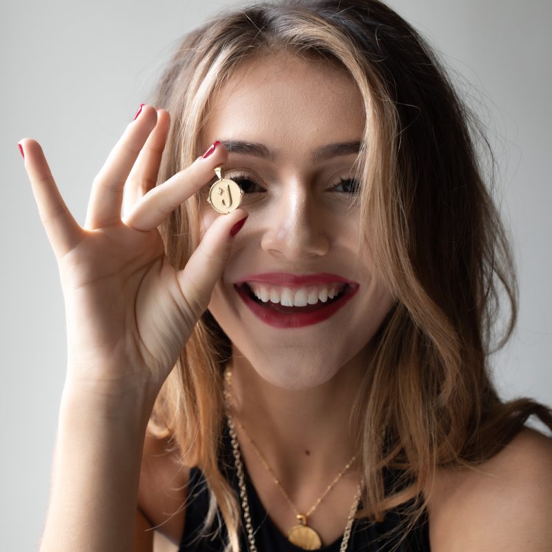 Model holding gold letter J coin